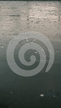 Closeup of rain drops falling on puddle with lights reflection on city sidewalk, Rain drop with street lights at night