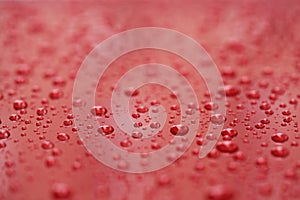 Closeup rain drops on red car with hydrophobic coating
