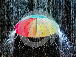 Closeup of a rainbow umbrella under the pouring monsoon rain in Malaysia