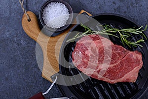 Closeup raw beef striploin steak on grill pan with rosemary