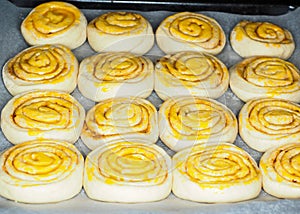 Closeup of raw cinnamon buns after proofing with egg yolk