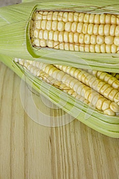 Closeup of raw corn cobs with straw over wood