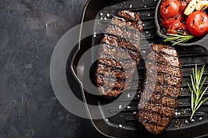 Closeup ready to eat steak Top Blade beef breeds of black Angus with grill tomato, garlic and on a wooden Board. The