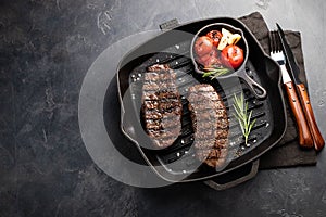 Closeup ready to eat steak Top Blade beef breeds of black Angus with grill tomato, garlic and on a wooden Board. The