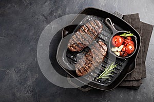 Closeup ready to eat steak Top Blade beef breeds of black Angus with grill tomato, garlic and on a wooden Board. The