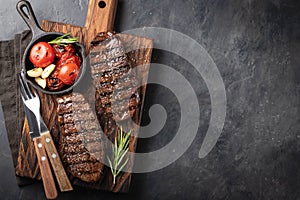 Closeup ready to eat steak Top Blade beef breeds of black Angus with grill tomato, garlic and on a wooden Board. The