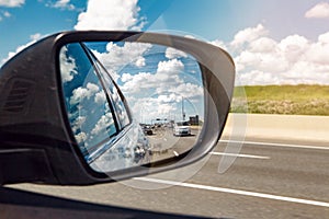 Closeup of rear back car mirror with beautiful landscape midday view of Toronto city highway street road.