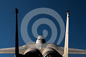 Closeup of rear of military supersonic jet F-15 eagle blue sky background