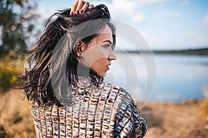 Closeup rear portrait of pretty female with blowing hair relaxing and enjoying nature next to the lake outdoors. Caucasian dreamy