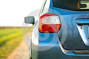 Closeup of rear red taillight and mirror of new clean blue SUV off-road car on rural road