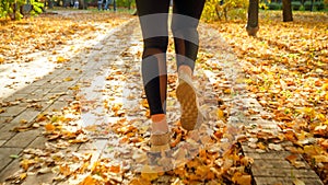 Closeup rear view photo of young woman in sportswear running and training in autumn park