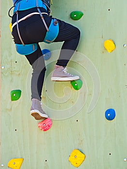 Closeup rear view young woman climbing wall sport safety . Challenge concept