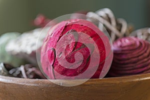 Closeup of red aromatic potpourri ball with natural pieces in wooden bowl