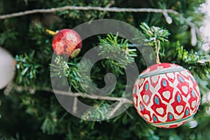 Closeup of red bauble hanging from a decorated Christmas tree.