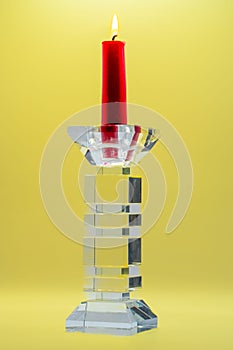 Closeup of a red candle in clear glass candelabra against the yellow background