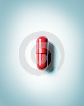 Closeup of red capsule on blue grey background