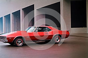 Closeup of a red Chevrolet Camaro with a building in the background