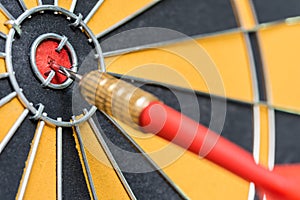 Closeup red dart arrow hitting in target bullseye of dartboard