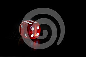 Closeup of a red dice with a winning number on the top face on a black mirror surface