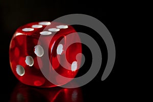 Closeup of a red dice with a winning number on the top face on a black mirror surface