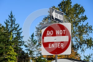 Closeup of red Do Not Enter sign and One Way sign on a sunny day, transportation directions