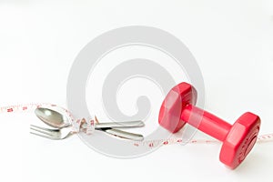 Closeup red dumbbells,fork and spoon with measuring tape