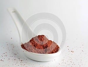 Closeup of red ground pepper on white spoon with a white background and copyspace on the top