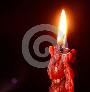 Closeup of red lit candle isolated on dark red background, fire, flame
