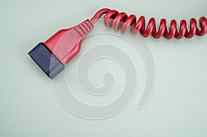 Closeup of a red networking cable with an electric plug on alight blue  background