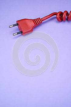 Closeup of a red networking cable with an electric plug on a light blue background