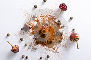 Top view of heap of red pepper powder, black peppercorns and dried red pepper on the white background