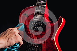 Closeup of a red shiny guitar body while being polished with a blue cloth