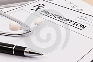 Closeup of red stethoscope and pen on a rx prescription.