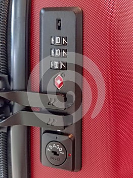 A closeup of a red travel suitcase with combination lock.