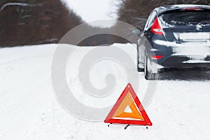 Closeup of red warning triangle with a broken down car