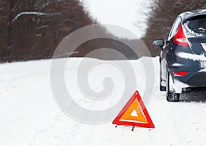 Closeup of red warning triangle with a broken down car