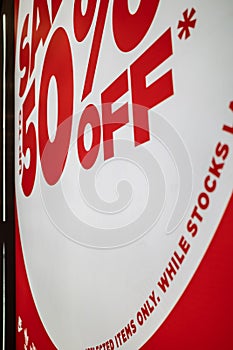 Closeup Red and White 50% Off Sale Sign on Fashion Store Exterior