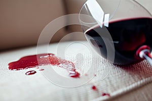 closeup of red wine spilled on white sofa cushion