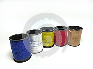 Closeup on reels of multicolored sewing threads in row isolated