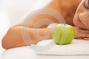 Closeup on relaxed young woman on massage table with apple
