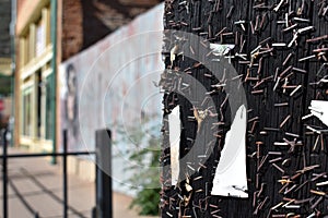 Closeup of remaining staples from multiple fliers on a bulletin board