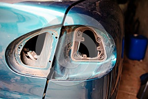 Closeup repairing of an broken blue car in garage by hands of machanic