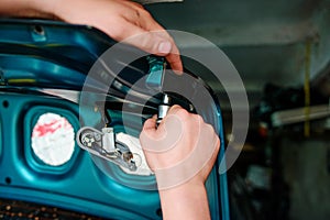 Closeup repairing of an broken blue car in garage by hands of machanic