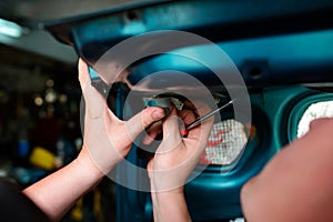 Closeup repairing of an broken blue car in garage by hands of machanic