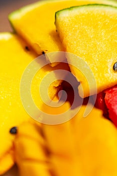 Closeup ripe juicy sliced fruits of mango and red and yellow watermelon. Sweet and colorful fruit plate