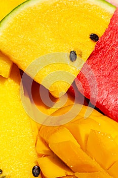 Closeup ripe juicy sliced fruits of mango and red and yellow watermelon. Sweet and colorful fruit plate