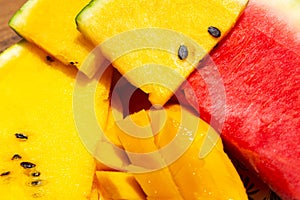 Closeup ripe juicy sliced fruits of mango and red and yellow watermelon. Sweet and colorful fruit plate