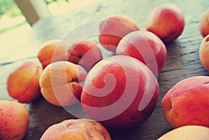 Closeup of ripe orange apricots on the rustic wooden table; filtered retro