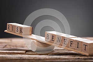 Closeup Of Risk And Benefit Wooden Blocks On Seesaw