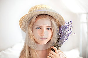 Closeup romantic portrait Charming little blond girl in a straw hat holds a bouquet of lavender. Summer flowers, aromatherapy. An